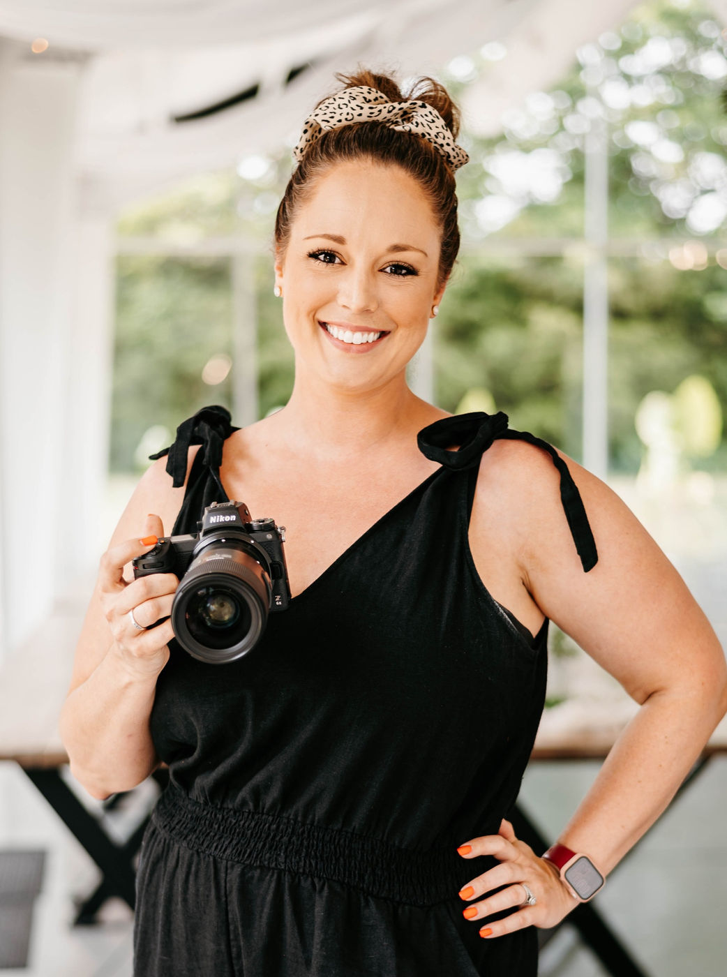 Amanda Bradley holding her camera in a bright white wedding venue